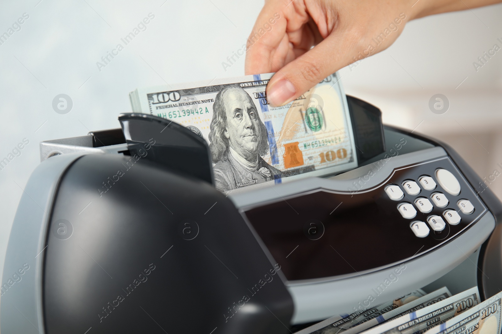 Photo of Woman putting money into counting machine indoors, closeup