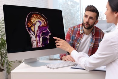 Photo of Neurologist showing brain scan to sad man in clinic