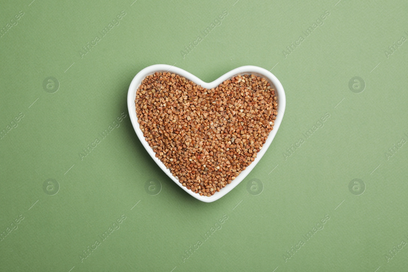 Photo of Buckwheat grains on green background, top view