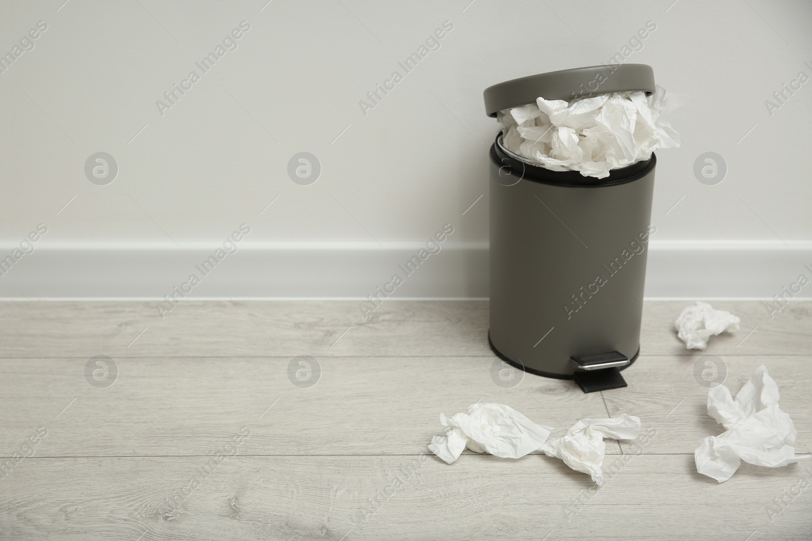 Photo of Used paper tissues and trash can on wooden floor. Space for text