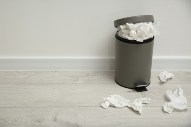 Photo of Used paper tissues and trash can on wooden floor. Space for text