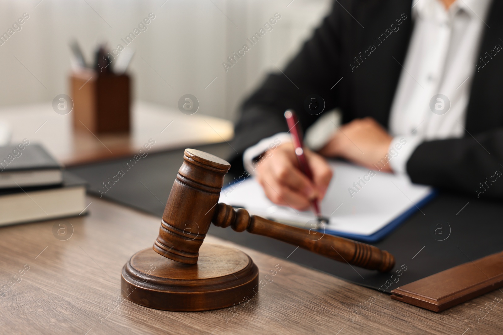 Photo of Notary with clipboard writing notes at workplace in office, focus on mallet