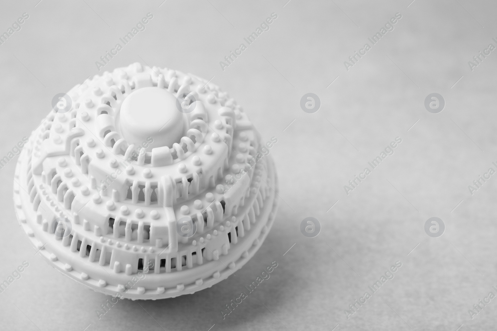 Photo of Laundry dryer ball on light grey table, closeup. Space for text