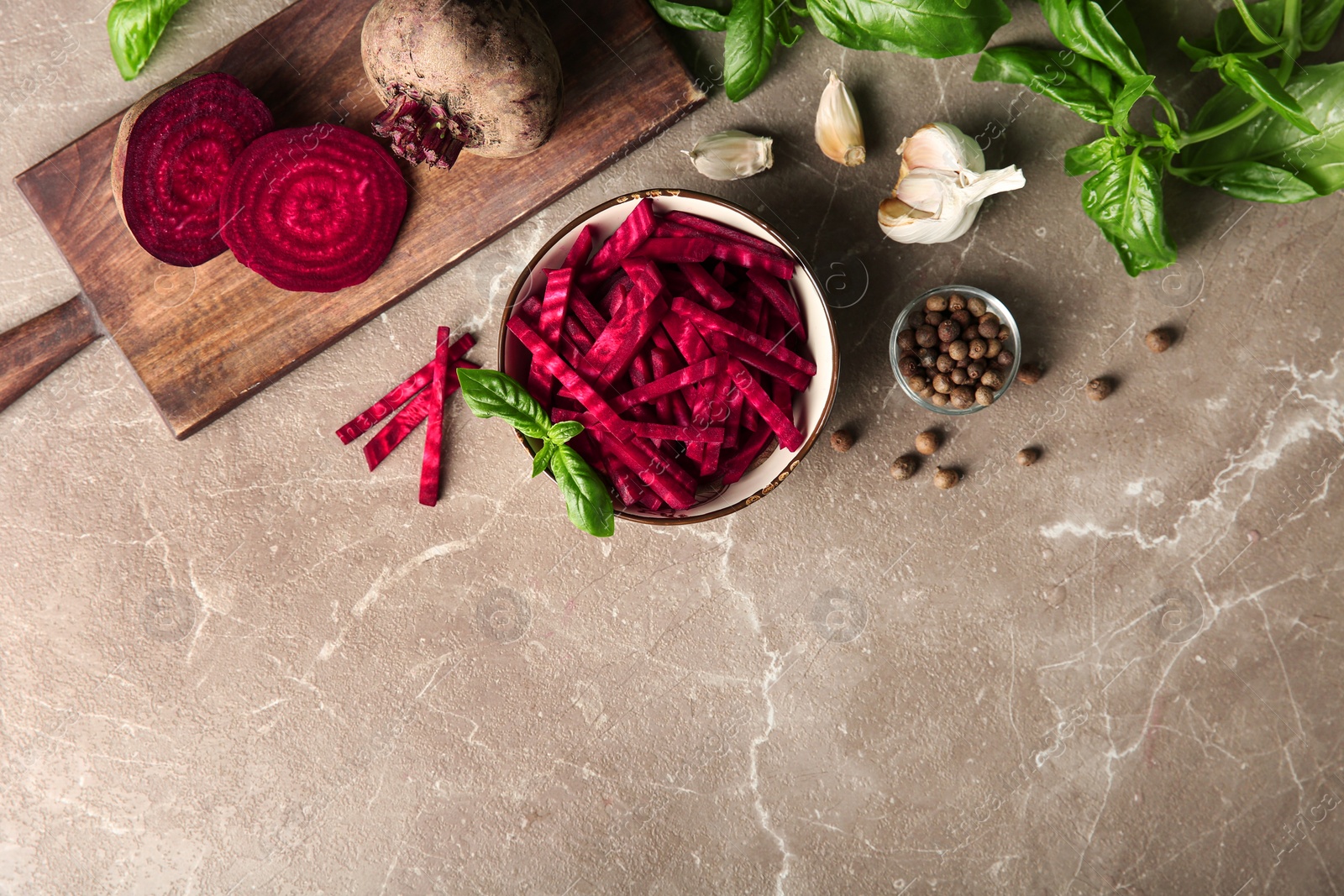 Photo of Bowl of cut fresh beets with basil, garlic and allspice on marble table, flat lay. Space for text