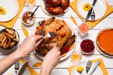 Woman eating traditional cooked turkey at white wooden table, top view. Thanksgiving day celebration