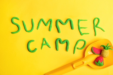 Photo of Flat lay composition with words SUMMER CAMP made from modelling clay and plastic shovel on color background