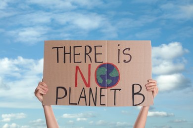 Image of Protestor holding placard with text There Is No Planet B against blue sky, closeup. Climate strike