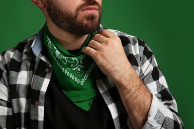 Photo of Fashionable young man in stylish outfit with bandana on green background, closeup