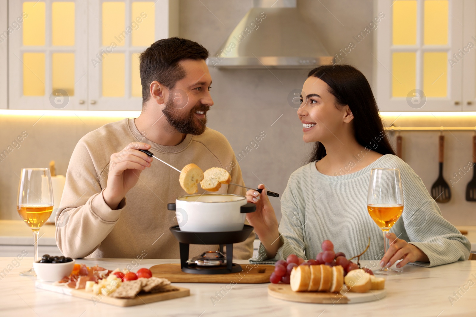 Photo of Affectionate couple enjoying fondue during romantic date in kitchen