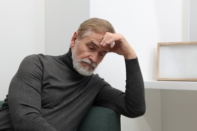 Upset senior man on sofa at home. Loneliness concept