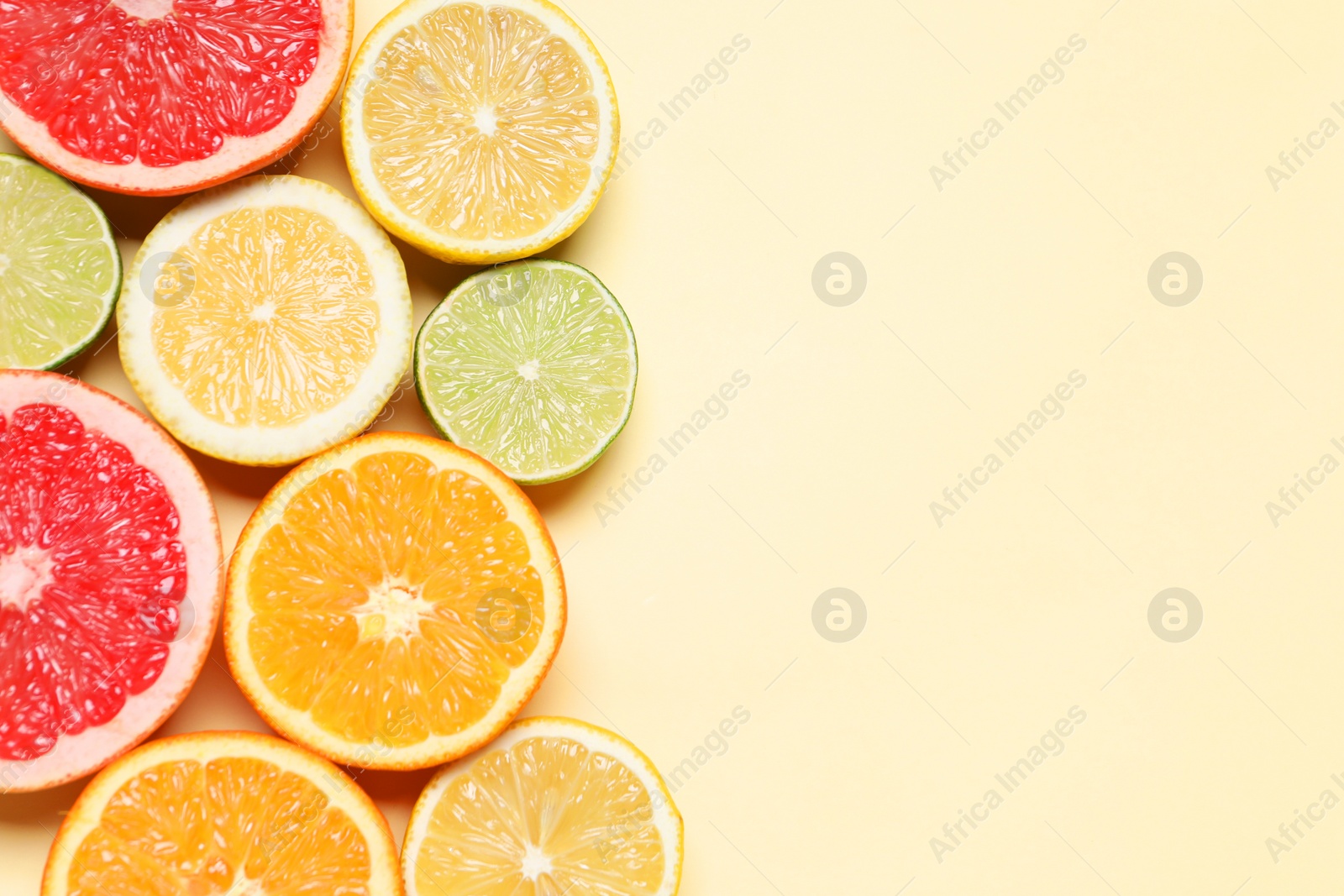 Photo of Different cut citrus fruits on beige table, flat lay. Space for text