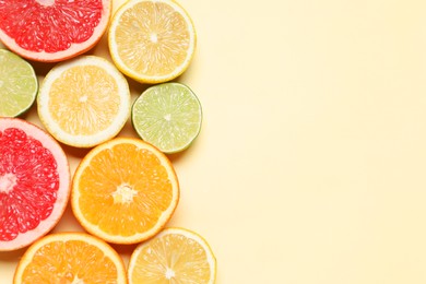 Photo of Different cut citrus fruits on beige table, flat lay. Space for text