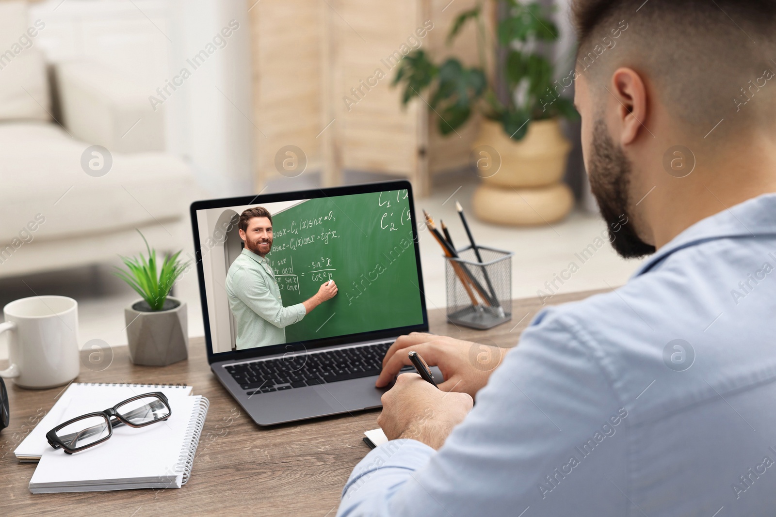 Image of E-learning. Young man having online lesson with teacher via laptop at home