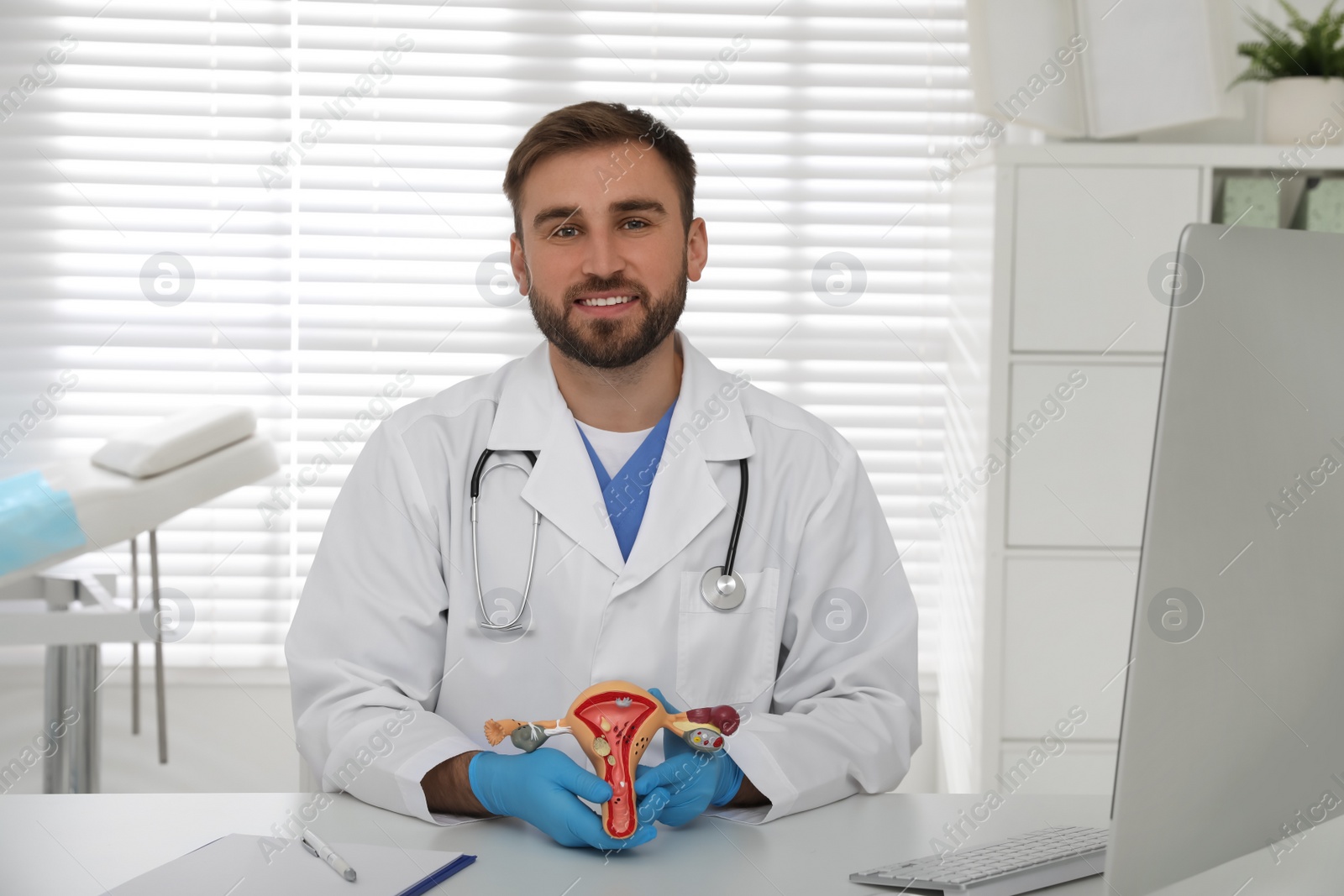 Photo of Gynecologist demonstrating model of female reproductive system at table in clinic