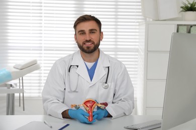 Gynecologist demonstrating model of female reproductive system at table in clinic