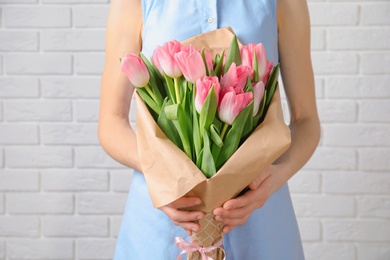 Photo of Girl holding bouquet of beautiful spring tulips near brick wall, closeup. International Women's Day