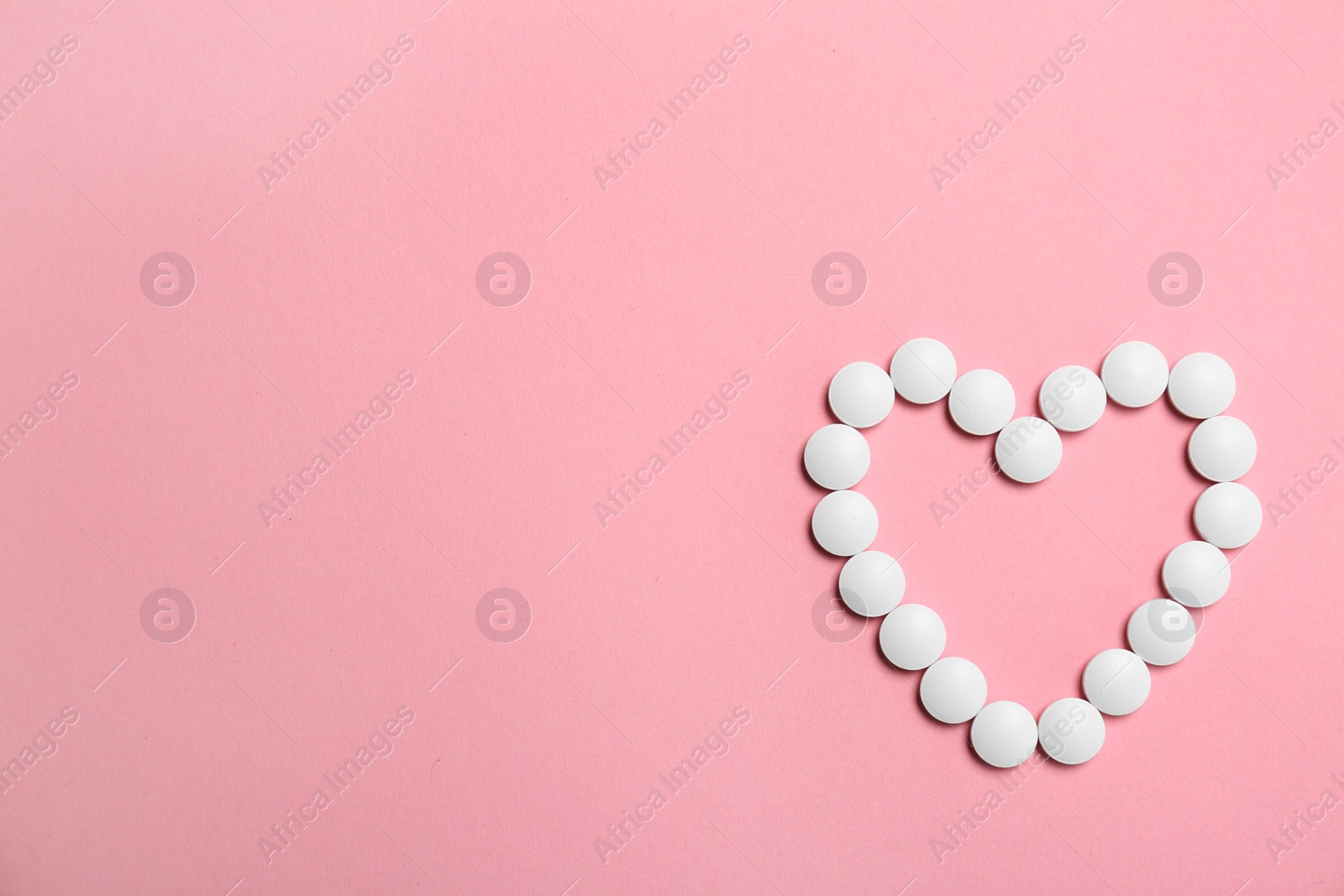 Photo of Heart made with white pills on color background