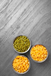 Open tin cans of conserved vegetables on grey table, flat lay with space for text