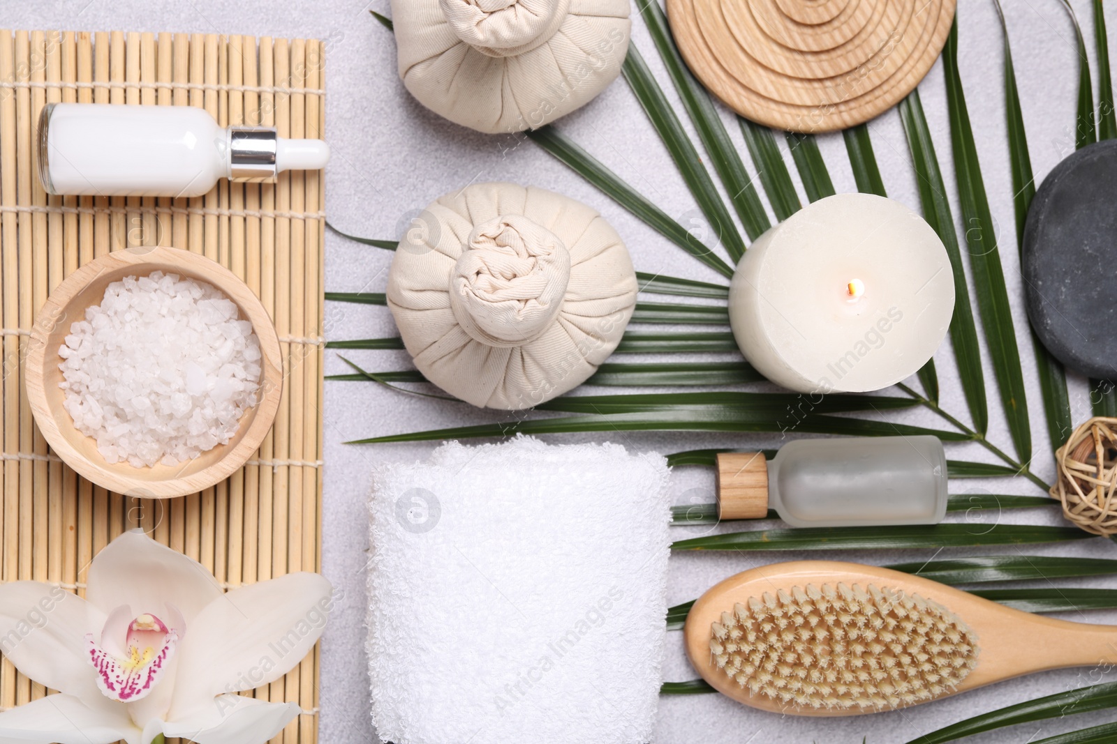 Photo of Flat lay composition with herbal massage bags, spa products and leaves on light grey table