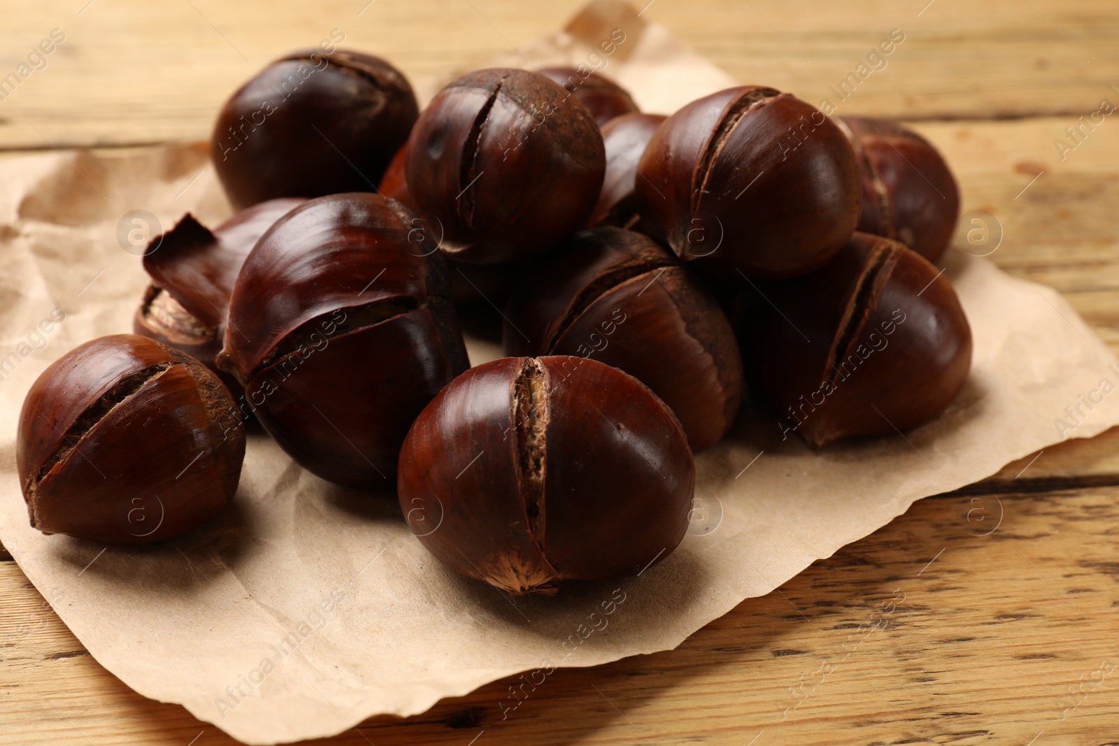 Photo of Fresh edible sweet chestnuts on wooden table, closeup