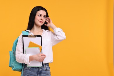 Photo of Student with notebooks and clipboard on yellow background. Space for text