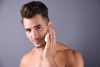 Photo of Handsome young man applying shaving foam on color background