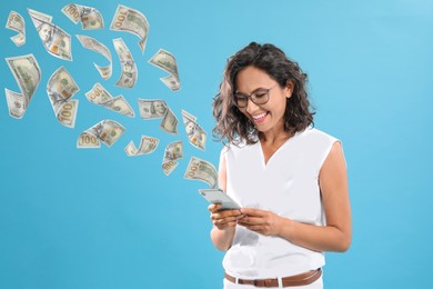 Online payment. Woman buying something using mobile phone on light blue background. Dollar banknotes flying out of gadget demonstrating process of money transaction