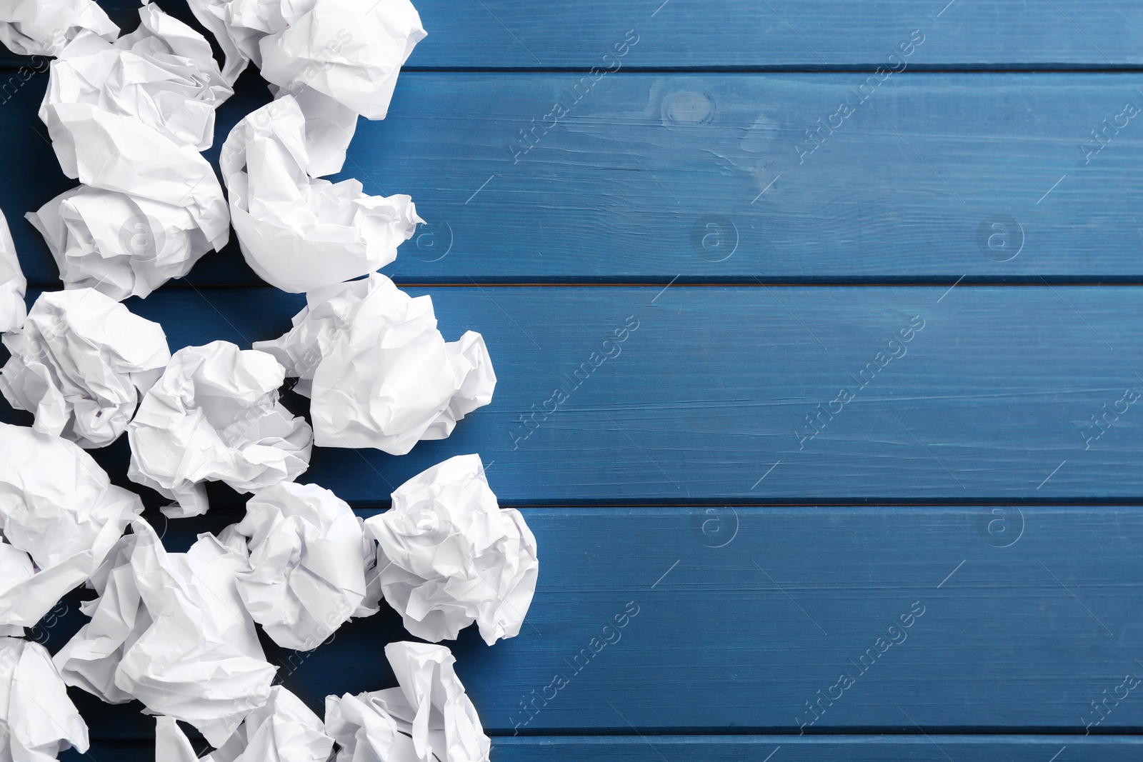 Photo of Crumpled sheets of paper on blue wooden background, flat lay. Space for text