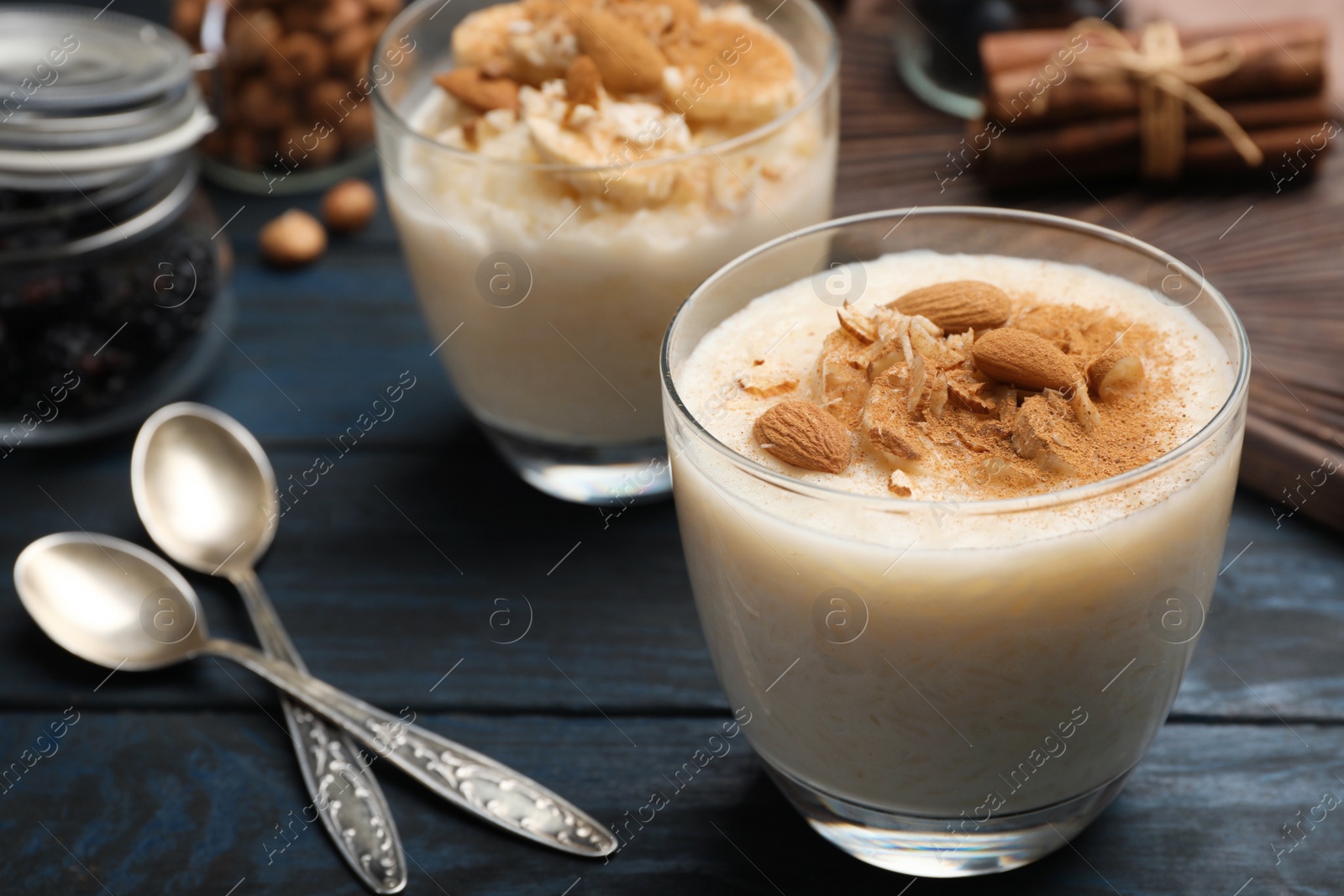 Photo of Delicious rice pudding with almonds and cinnamon on dark wooden table