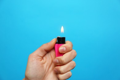 Photo of Woman holding pink lighter on light blue background, closeup