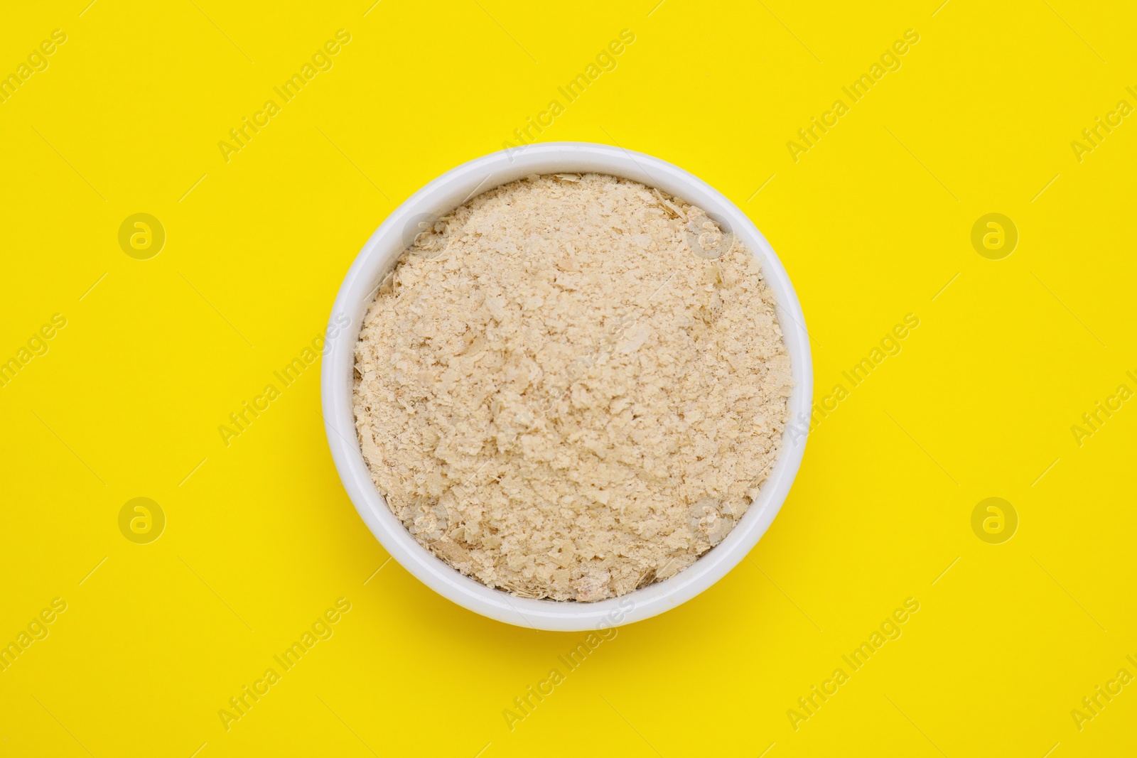 Photo of Beer yeast flakes on yellow background, top view