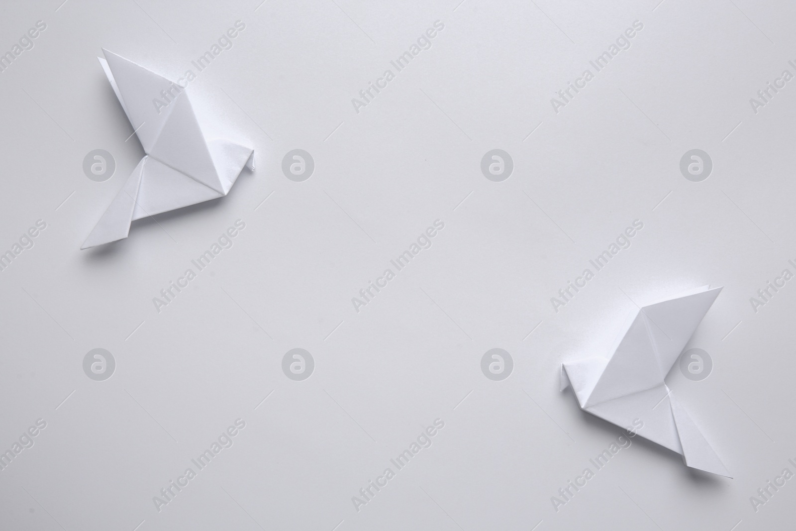 Photo of Beautiful origami birds on white background, flat lay. Space for text