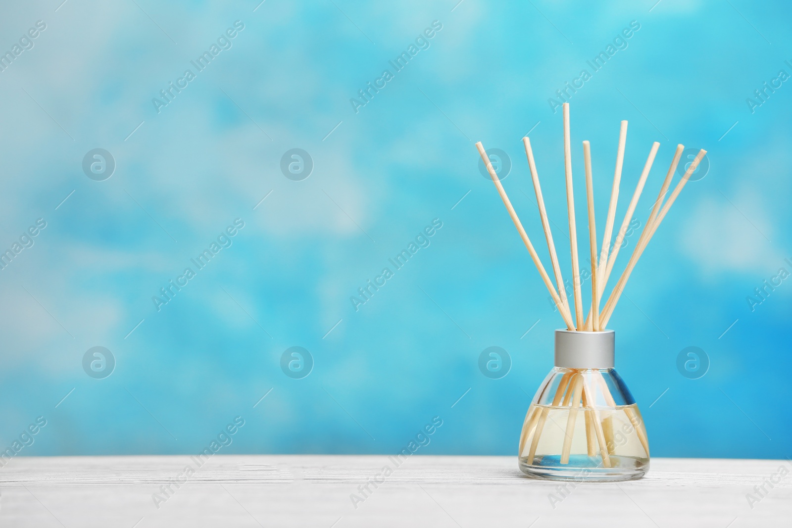 Photo of Aromatic reed freshener on table against color background