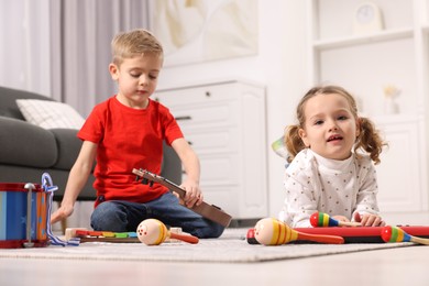 Little children playing toy musical instruments at home