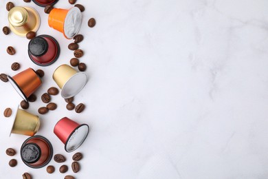 Photo of Many coffee capsules and beans on white marble table, flat lay. Space for text
