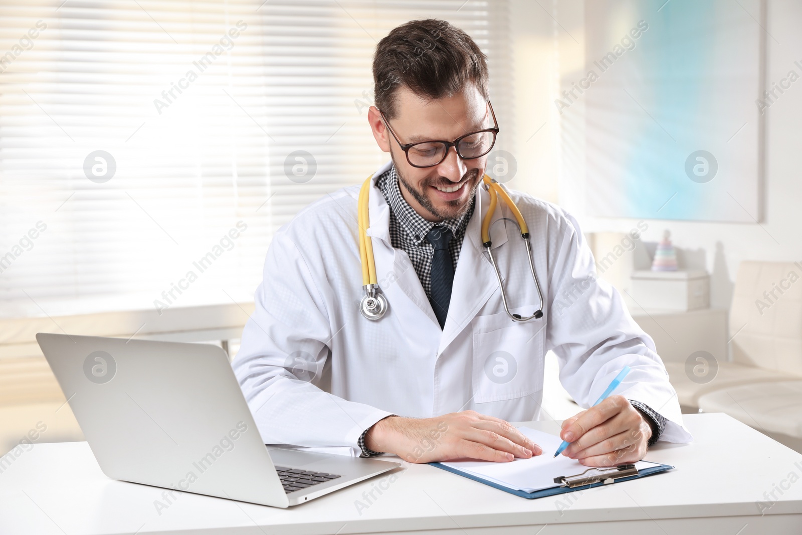 Photo of Pediatrician with stethoscope working at table in clinic