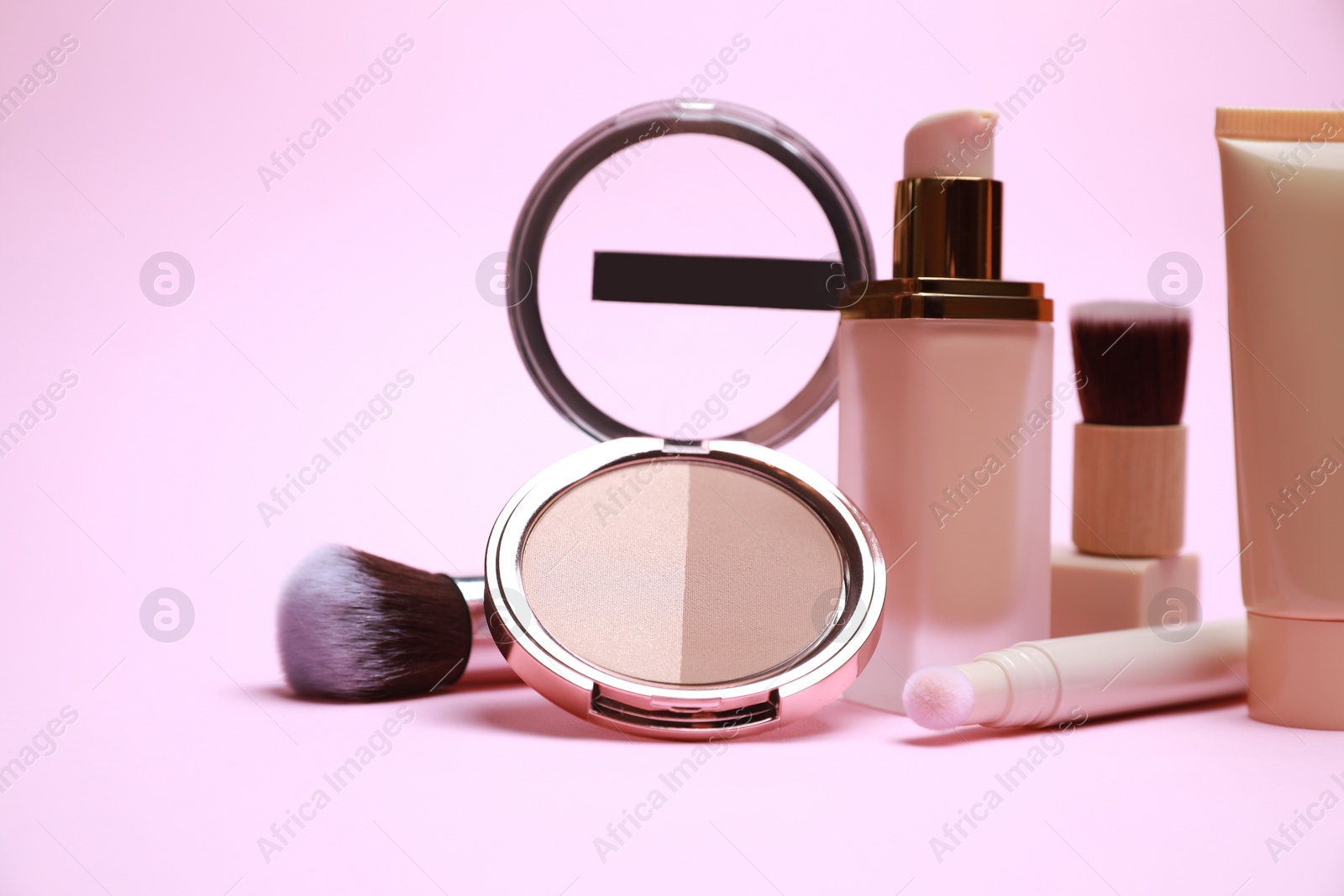 Photo of Face powder and other decorative cosmetic products on pink background