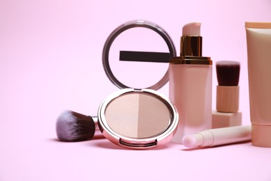 Face powder and other decorative cosmetic products on pink background
