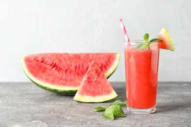 Photo of Tasty summer watermelon drink in glass and sliced fruit on table