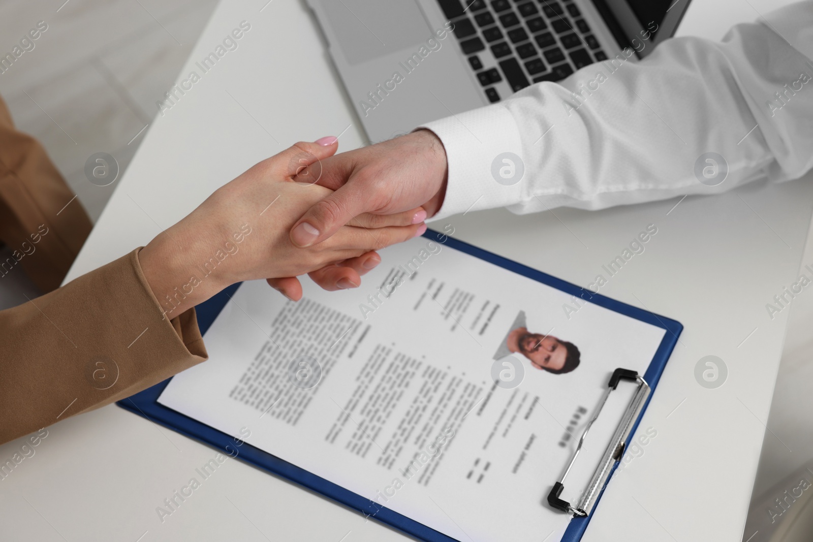 Photo of Human resources manager shaking hands with applicant during job interview in office, above view