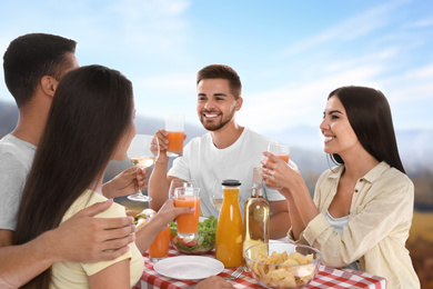 Image of Group of friends having picnic at table in park