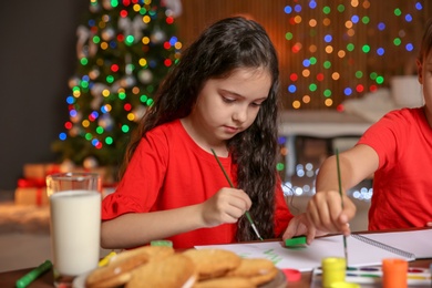 Photo of Little children painting pictures at home. Christmas celebration