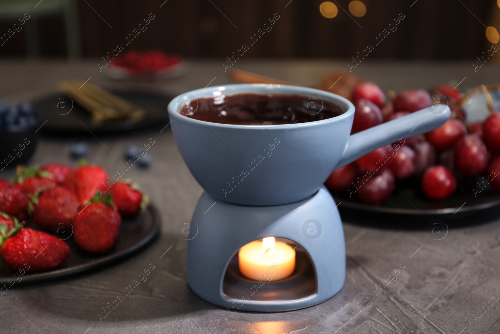 Photo of Ceramic pot with chocolate fondue on stone table