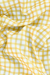 Yellow checkered picnic tablecloth as background, top view