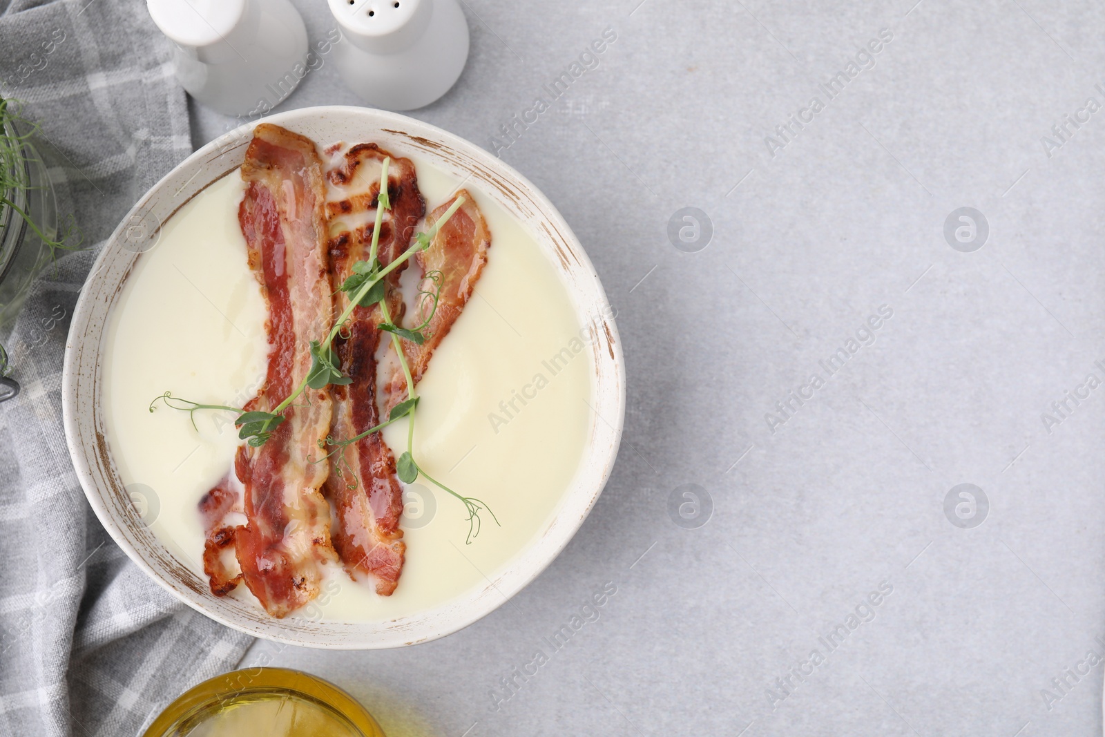 Photo of Delicious potato soup with bacon and microgreens on grey table, top view. Space for text