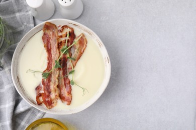 Delicious potato soup with bacon and microgreens on grey table, top view. Space for text