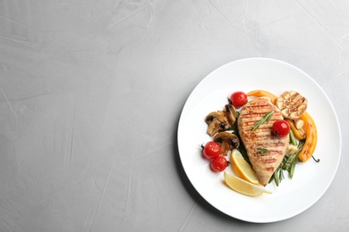 Tasty grilled chicken fillet with vegetables on light grey table, top view. Space for text