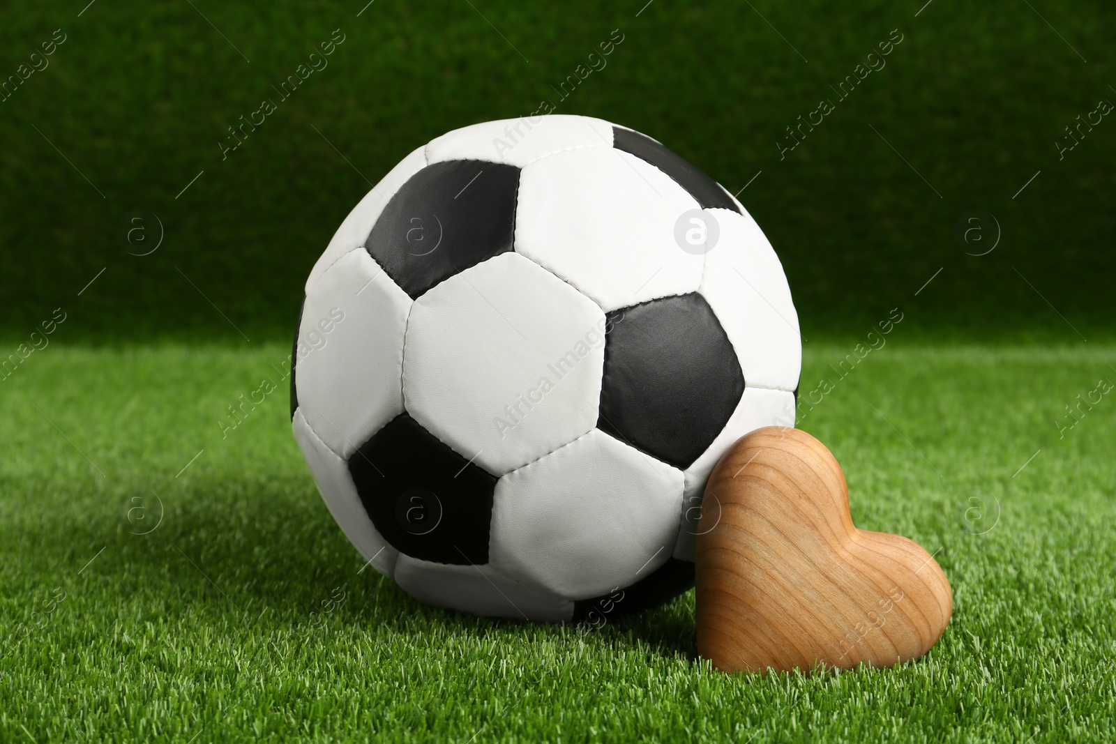 Photo of Soccer ball and heart on green grass