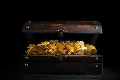 Image of Open treasure chest with gold coins on black wooden table