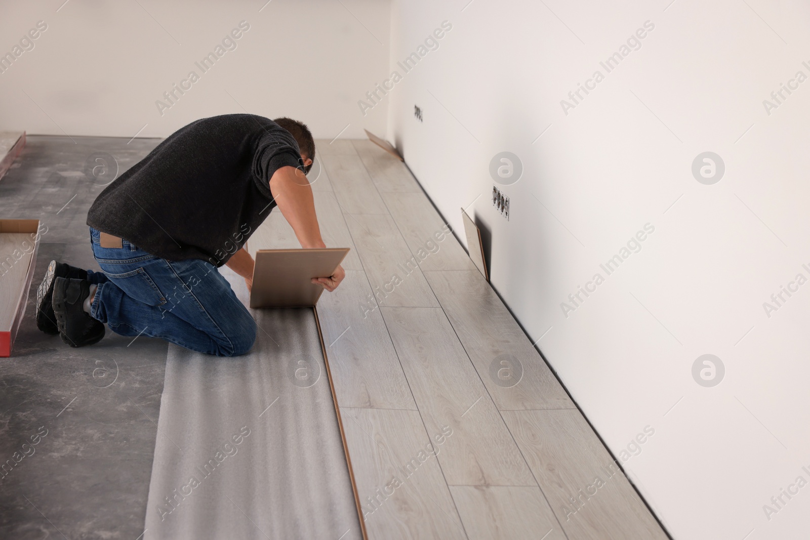 Photo of Professional worker installing new laminate flooring. Space for text